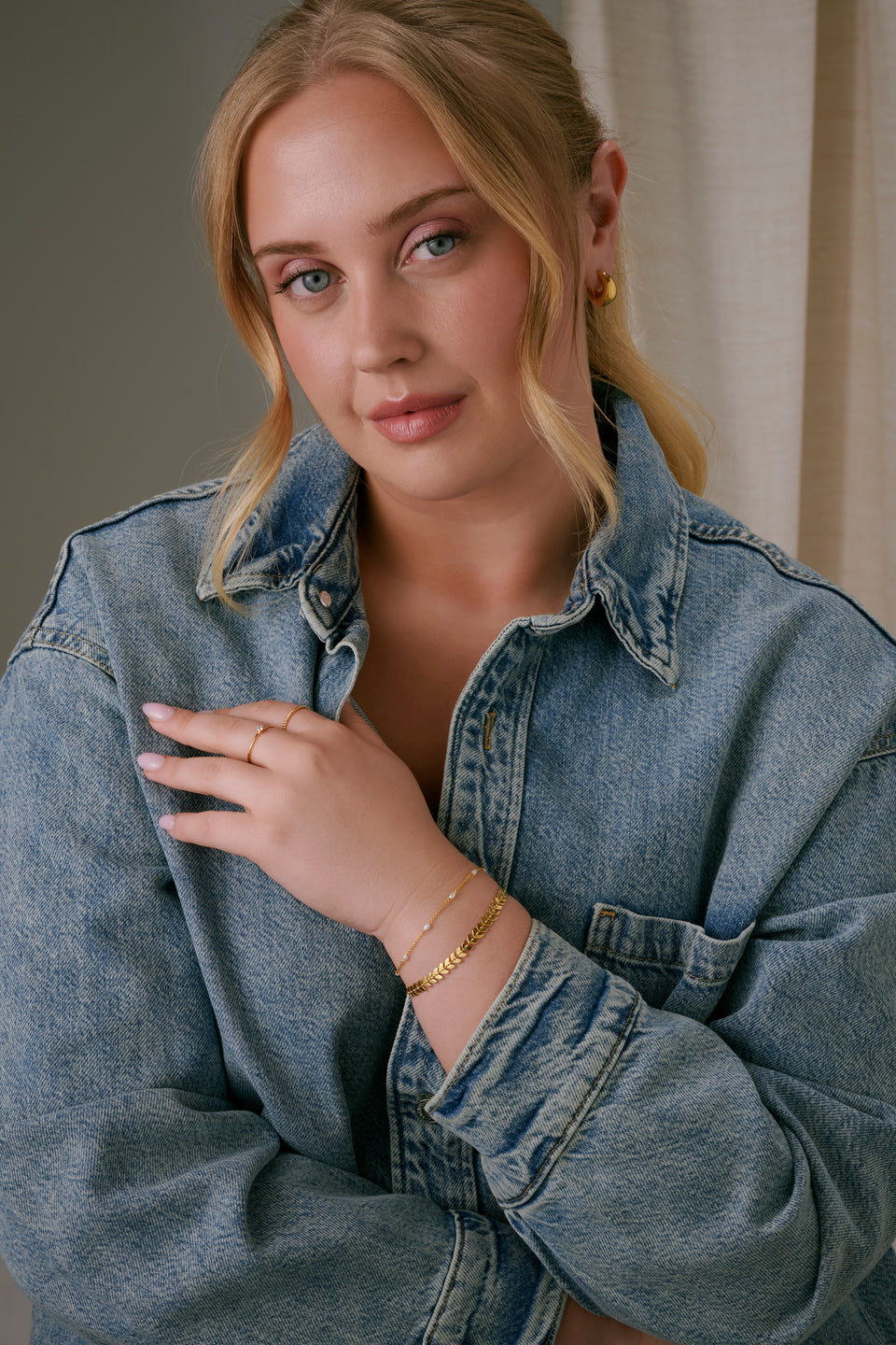 A gold bracelet with a layered design, styled with a thin gold bracelet with pearls