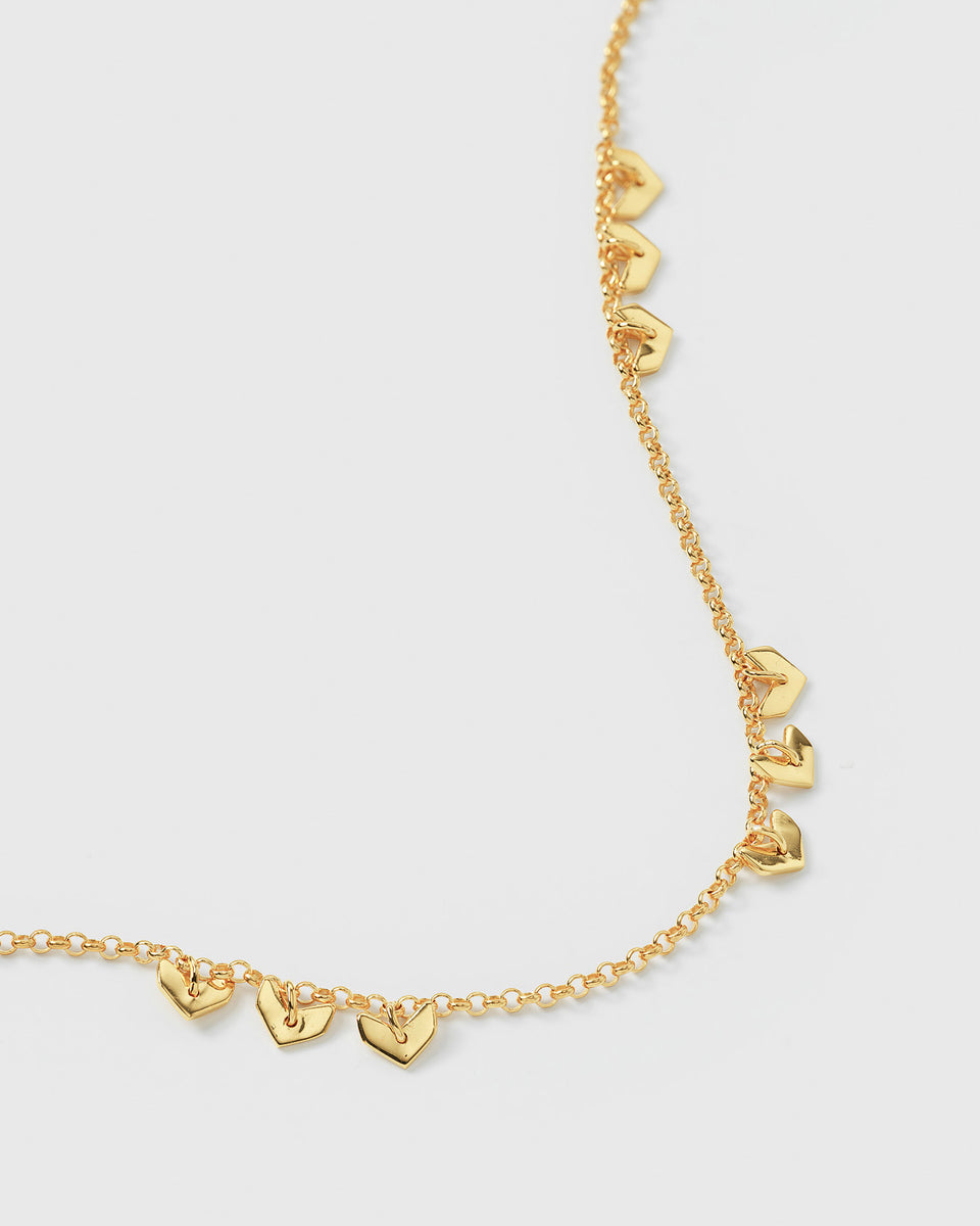 Close-up of the handmade Layers Bianca Bracelet in gold, showing the delicate chain made from 100% recycled sterling silver plated with 18K gold and adorned with sweet, small leaf-like charms.