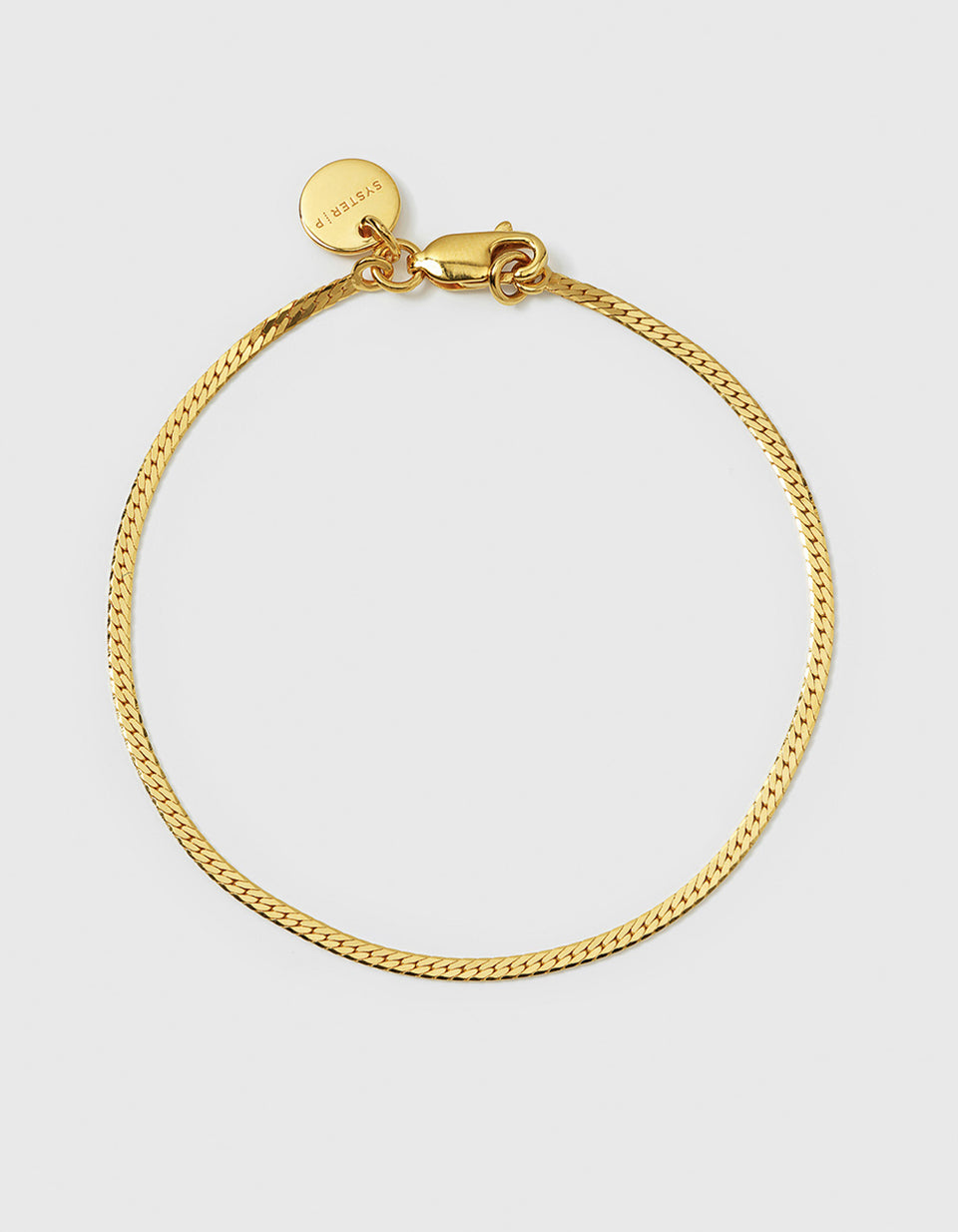 A product shot of the Syster P Herringbone Bracelet in gold, laid out in a circle to display its smooth, flat chain design.