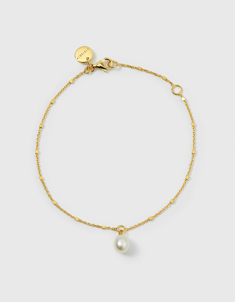A product shot of the gold Treasure Single Pearl Bracelet, laid out in a circle to display its unique chain with tiny, shining dots and a single teardrop-shaped freshwater pearl charm.