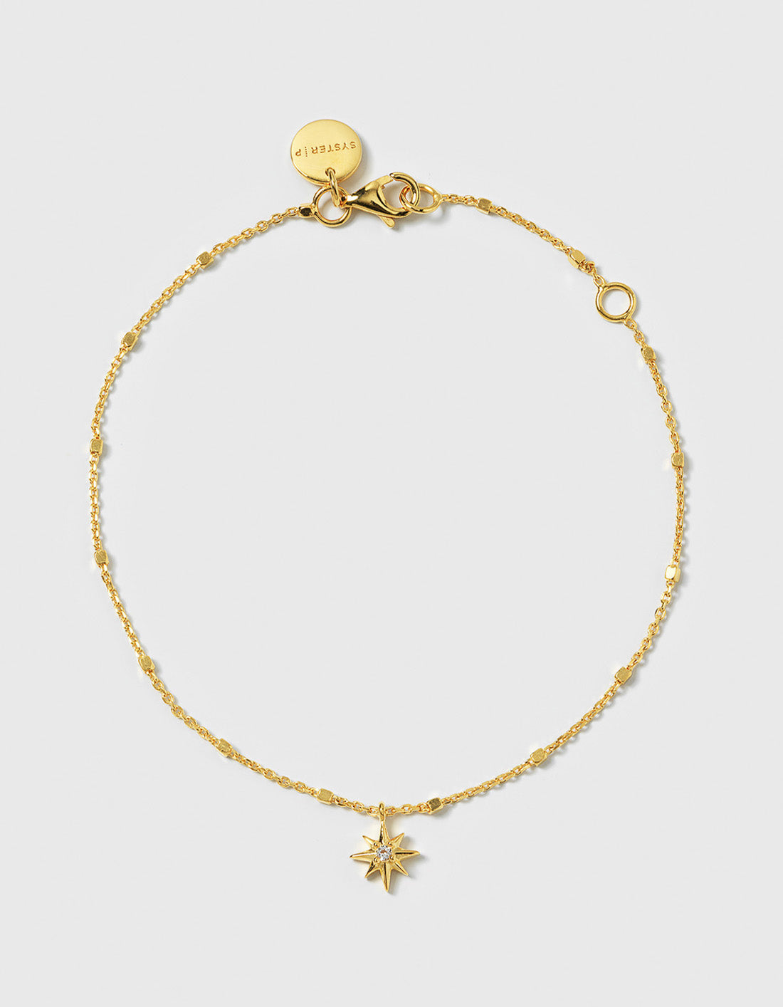 A product shot of the North Star Bracelet in gold, laid out in a circle. The bracelet features a delicate chain and a North Star charm set with a single sparkling crystal.