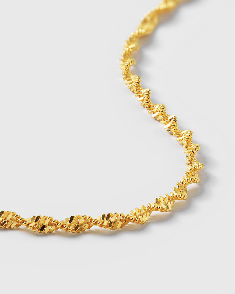 A close-up product shot of the Herringbone Twisted Bracelet in gold, showcasing the intricate details of its twisted chain design.