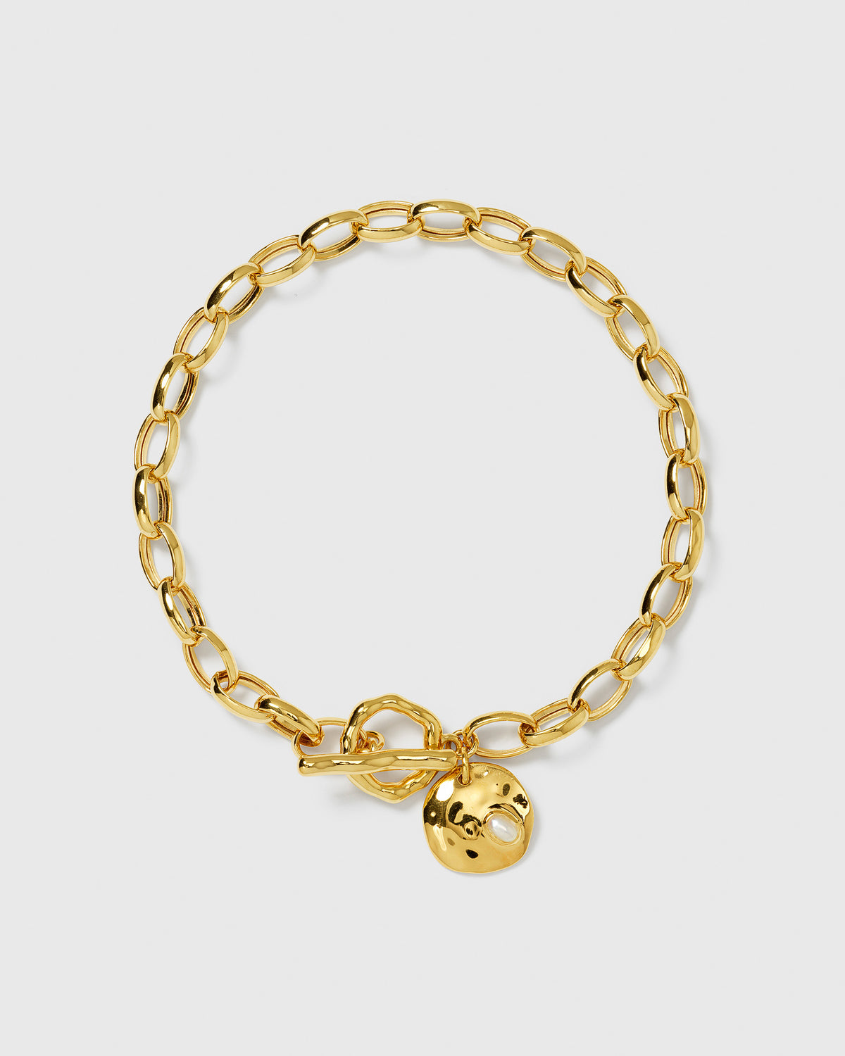 The Paxton Heavy Bracelet in gold, featuring a heavy link chain, a toggle clasp, and a hammered pendant with a set baroque freshwater pearl.