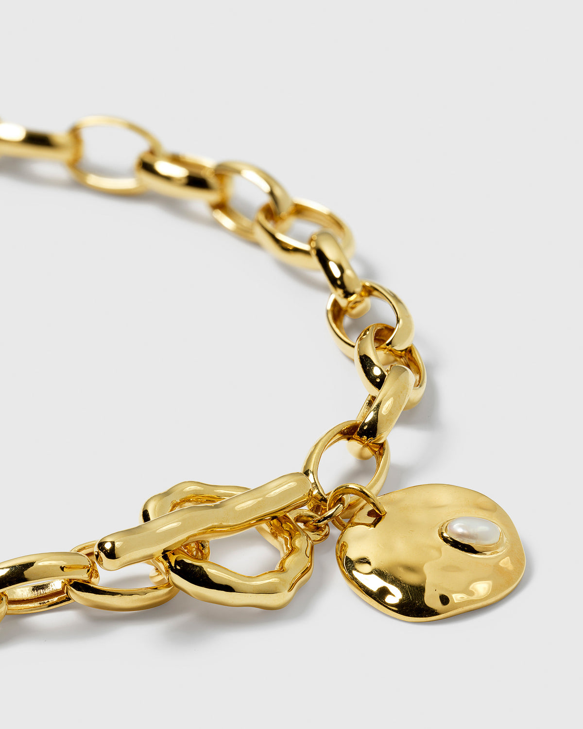 Close-up of the Paxton Heavy Bracelet in gold, showing the details of the toggle clasp and the hammered pendant with its set baroque pearl.