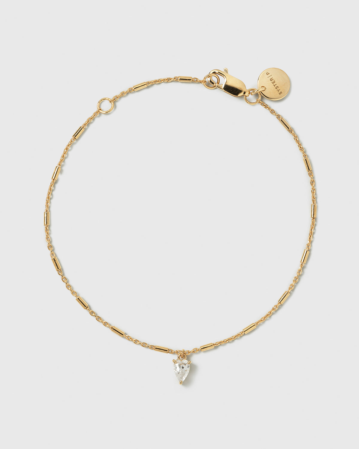 A product shot of the Katie Bracelet in gold, featuring a delicate chain with small bar accents and a drop-shaped cubic zirconia charm.