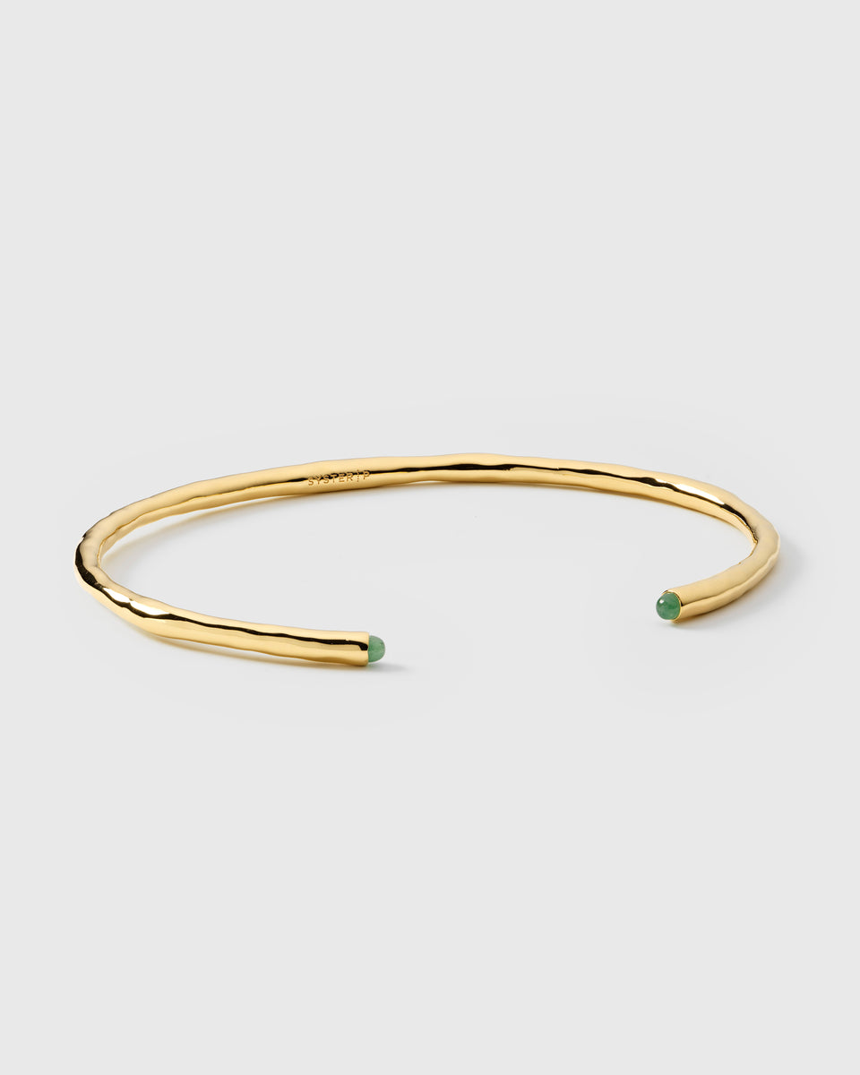 A product shot of the Florentina Bangle in gold, featuring its hammered surface and the green jade stones set at each open end.