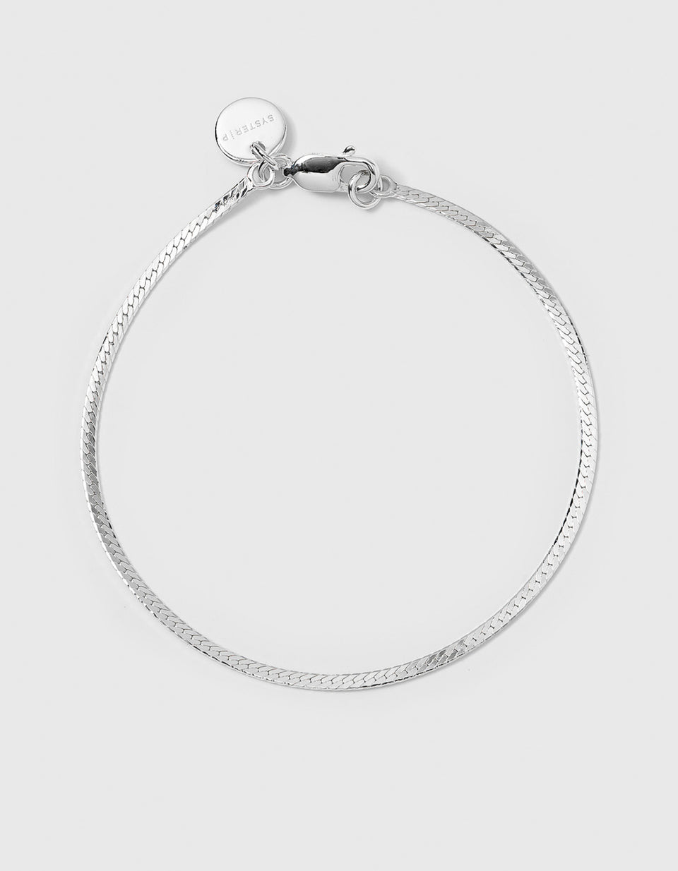 A product shot of the Herringbone Bracelet in silver, laid out in a circle to display its classic flat, woven chain.