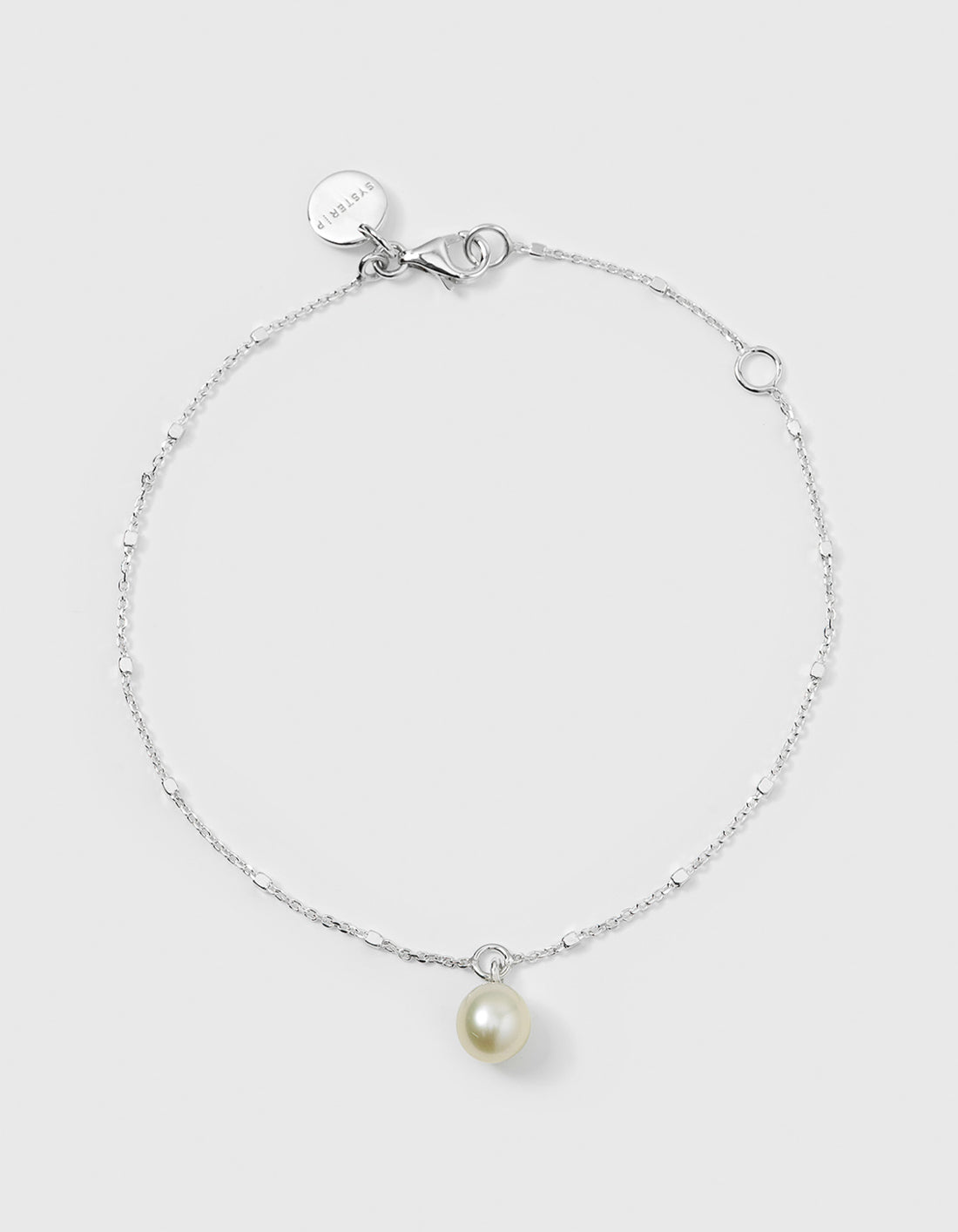 A product shot of the Treasure Single Pearl Bracelet in silver, laid out in a circle to show its unique chain with tiny shining dots and a single teardrop-shaped freshwater pearl charm.