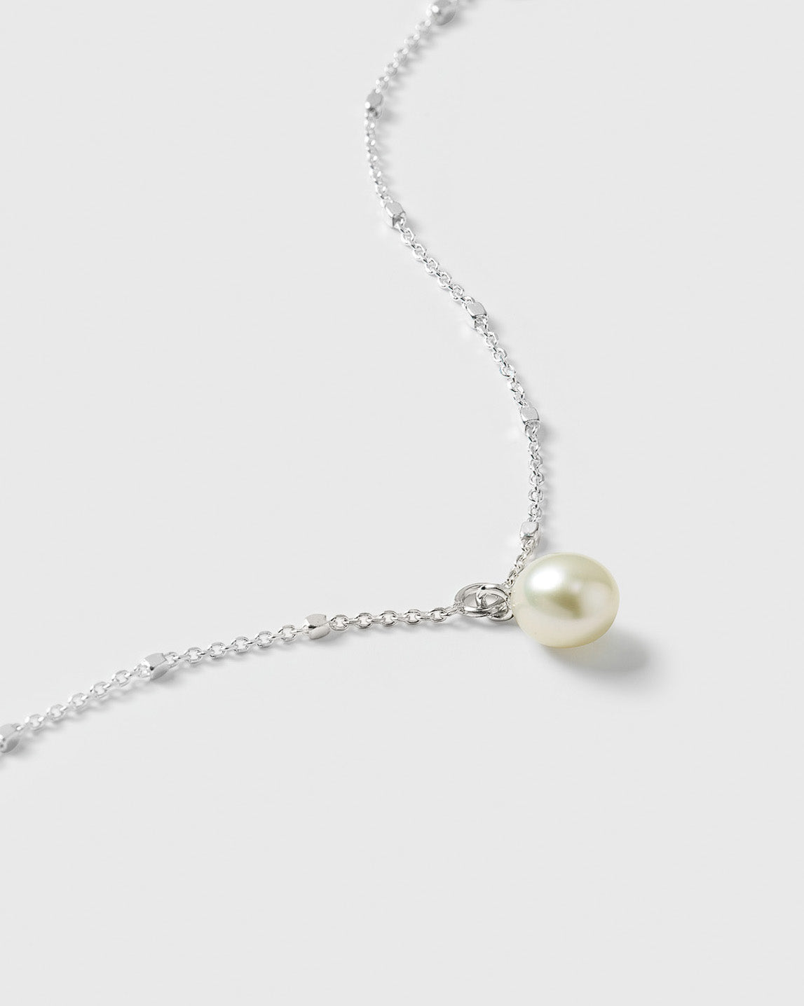 A close-up of the Treasure Single Pearl Bracelet in silver, showcasing its unique, delicate chain with tiny shining dots and a single, round freshwater pearl.