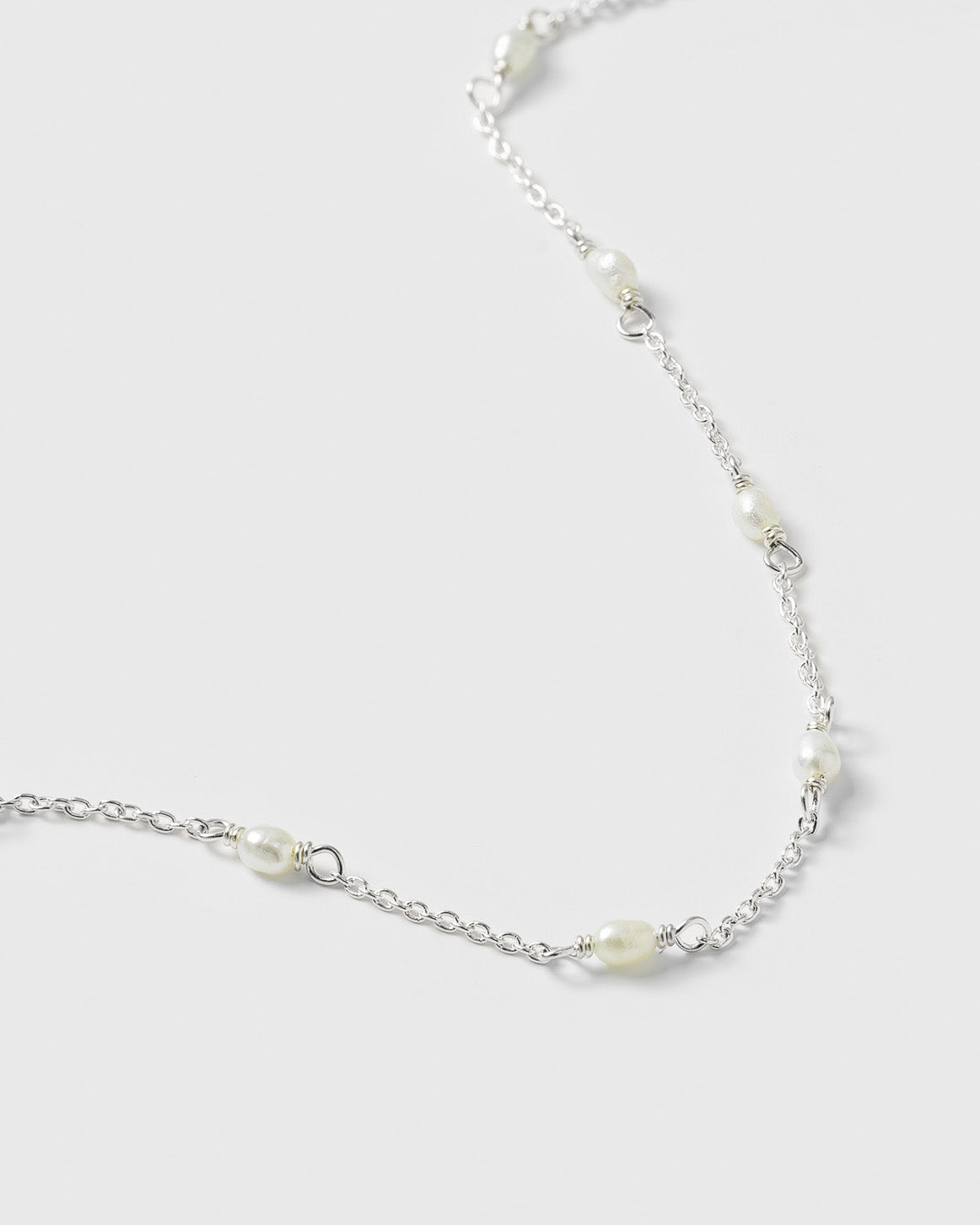 A close-up product shot of the Treasure Multi Pearl Bracelet in silver, highlighting its delicate chain design interspersed with small, oval freshwater pearls.