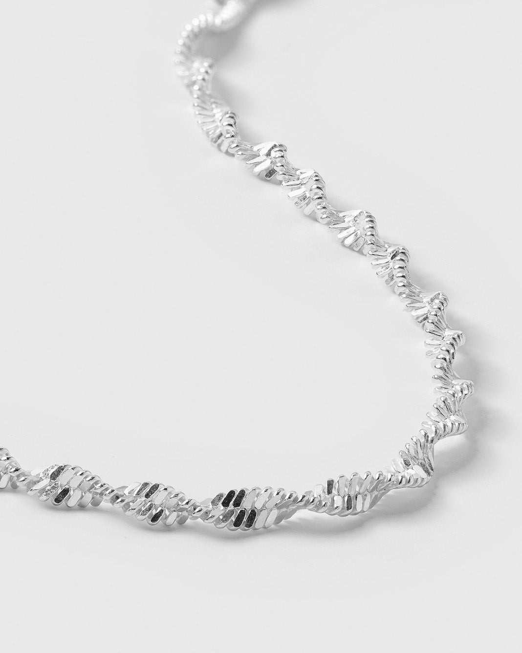 A close-up product shot of the Herringbone Twisted Bracelet in silver, showcasing the intricate, twisted design of the chain.