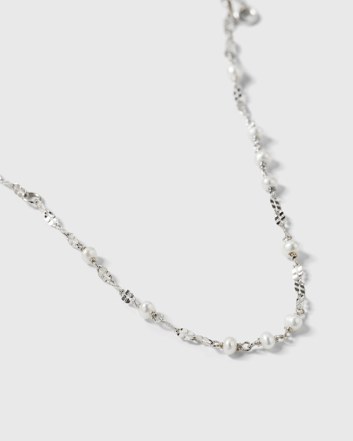 A close-up product shot of the Aurelia Bracelet in silver, highlighting its unique, light-catching chain interspersed with small freshwater pearls.