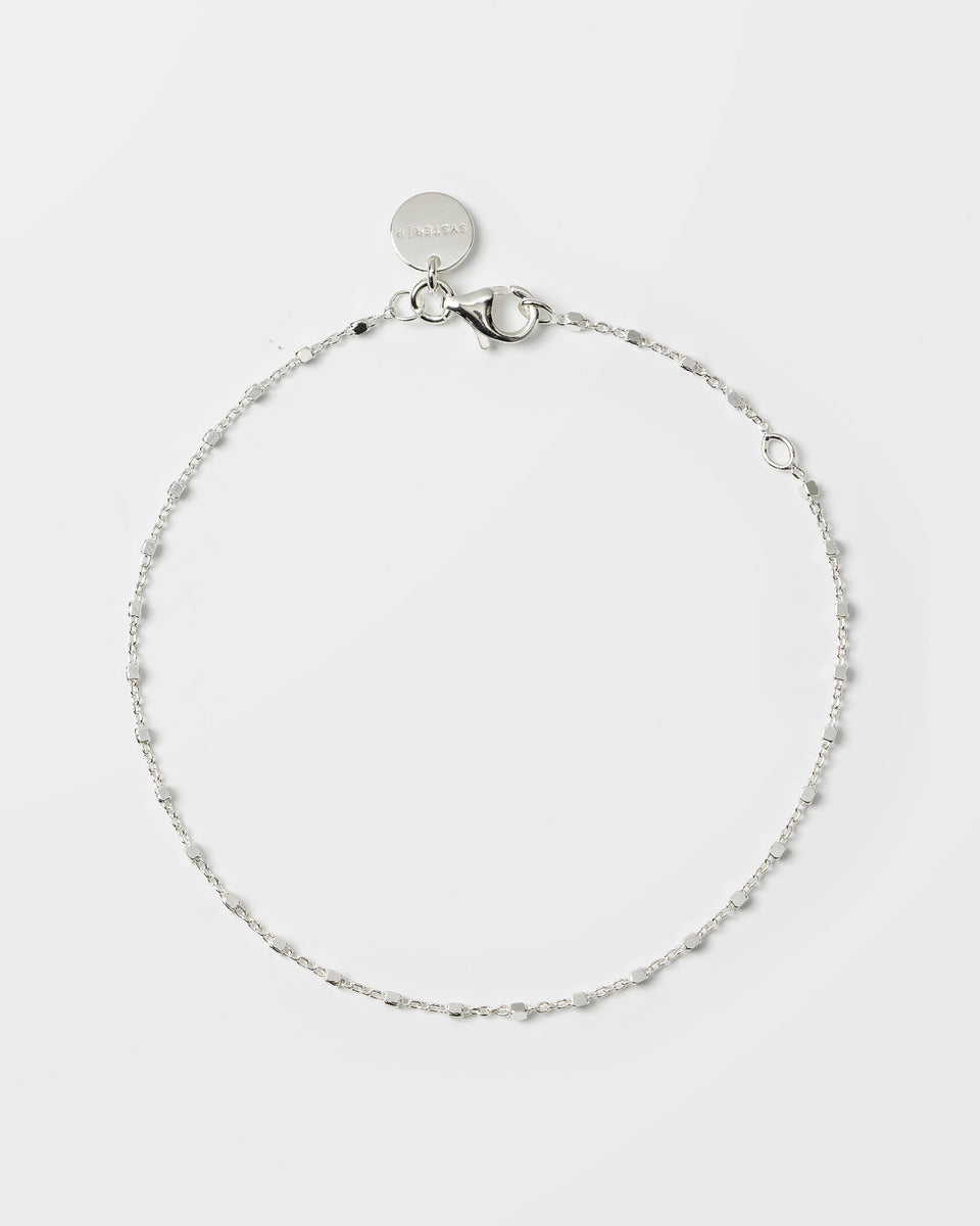 A product shot of the Sheer Station Bracelet in silver, laid out in a circle to display its fine chain design adorned with small, evenly spaced square beads.