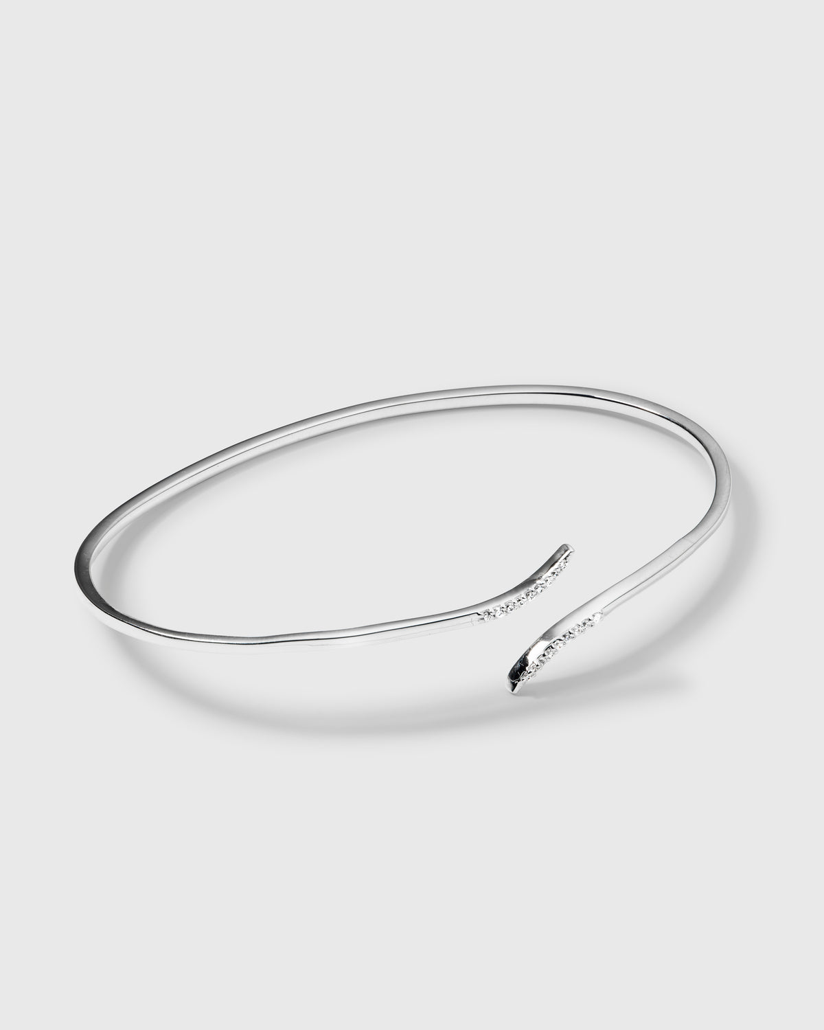A product shot of the Sparkle Wrap Bangle in silver, highlighting its delicate wrap design and the sparkling cubic zirconia stones set into its curved ends.