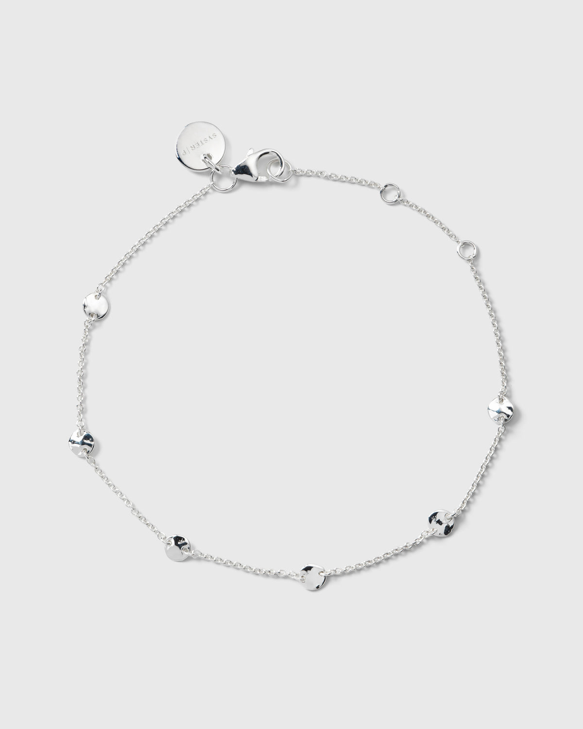 A product shot of the Solea Bracelet in silver, laid out in a circular shape to showcase its delicate chain and small, round hammered circles spaced thorughout.