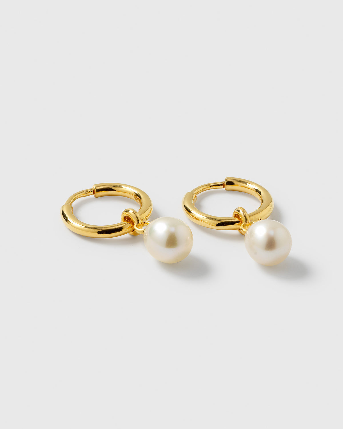 A product shot of the Treasure Pearl Hoops Gold, showing the pair of small gold hoops each with a dangling freshwater pearl.