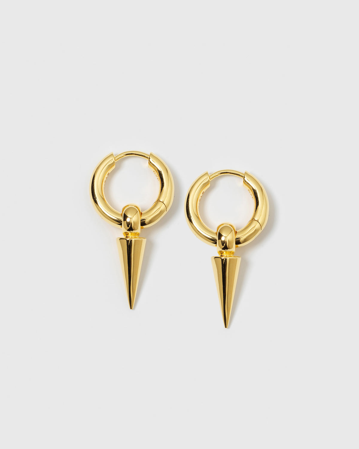 A product shot of the Juno Hoops in gold, featuring a pair of thick hoop earrings, each adorned with a dangling spike charm.