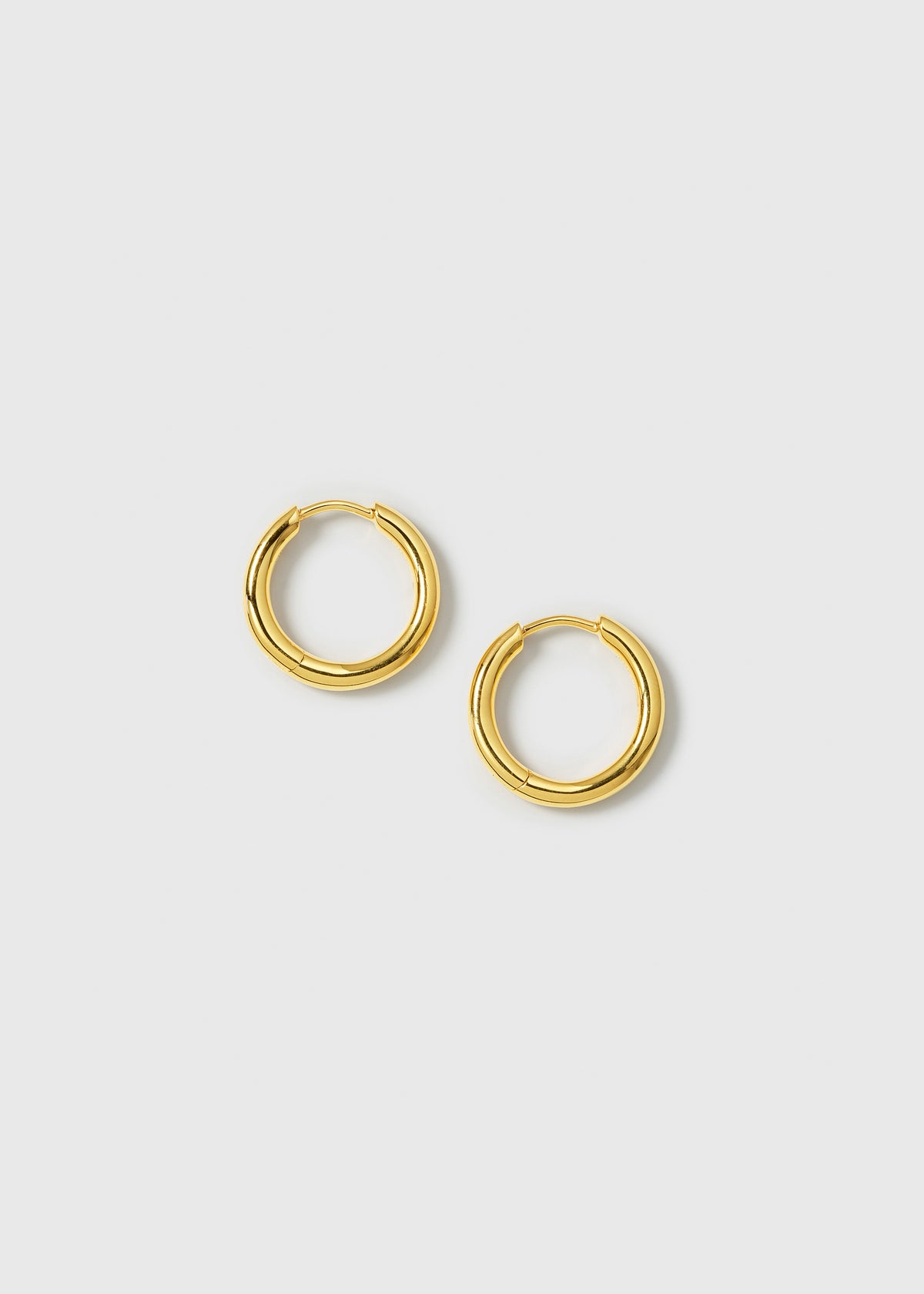 A product shot of the Beloved Fat Medium Hoops in gold, laid out to showcase their classic and chunky design.
