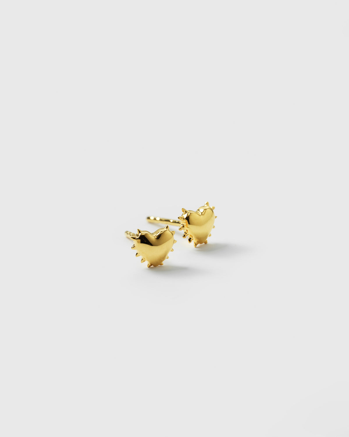 A product shot of the True Love Spike Heart Studs in gold, featuring the pair of heart-shaped earrings with a distinctive spiked border.