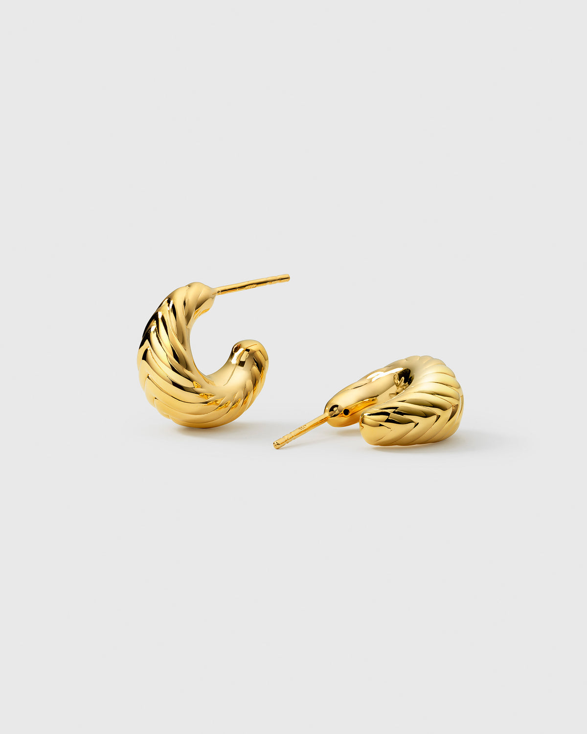 A product shot of the Bolded Little Sis Chevron Earrings in gold, showcasing their chunky, curved design with a detailed chevron pattern.