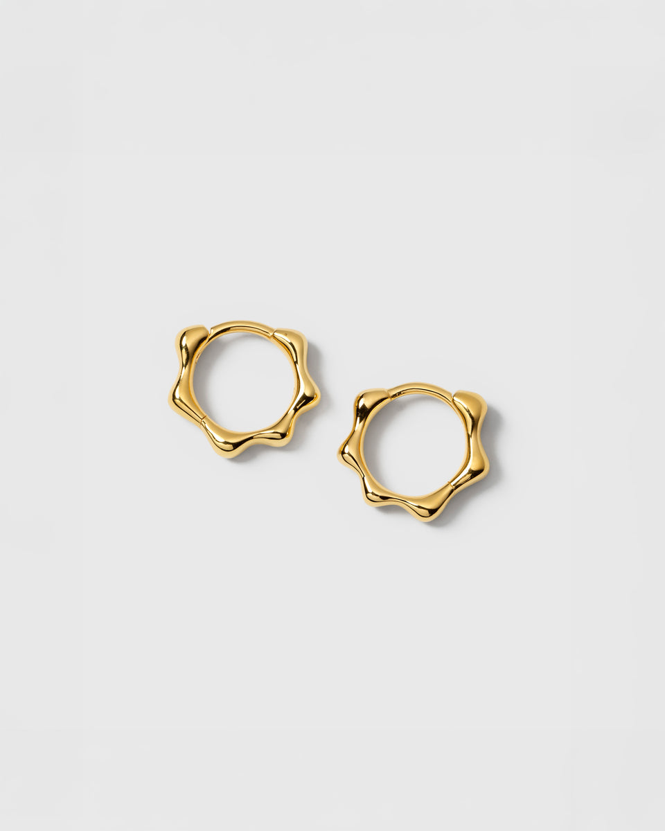 A product shot of the Florentina Small Hoops in gold, showcasing their unique, wavy pattern.