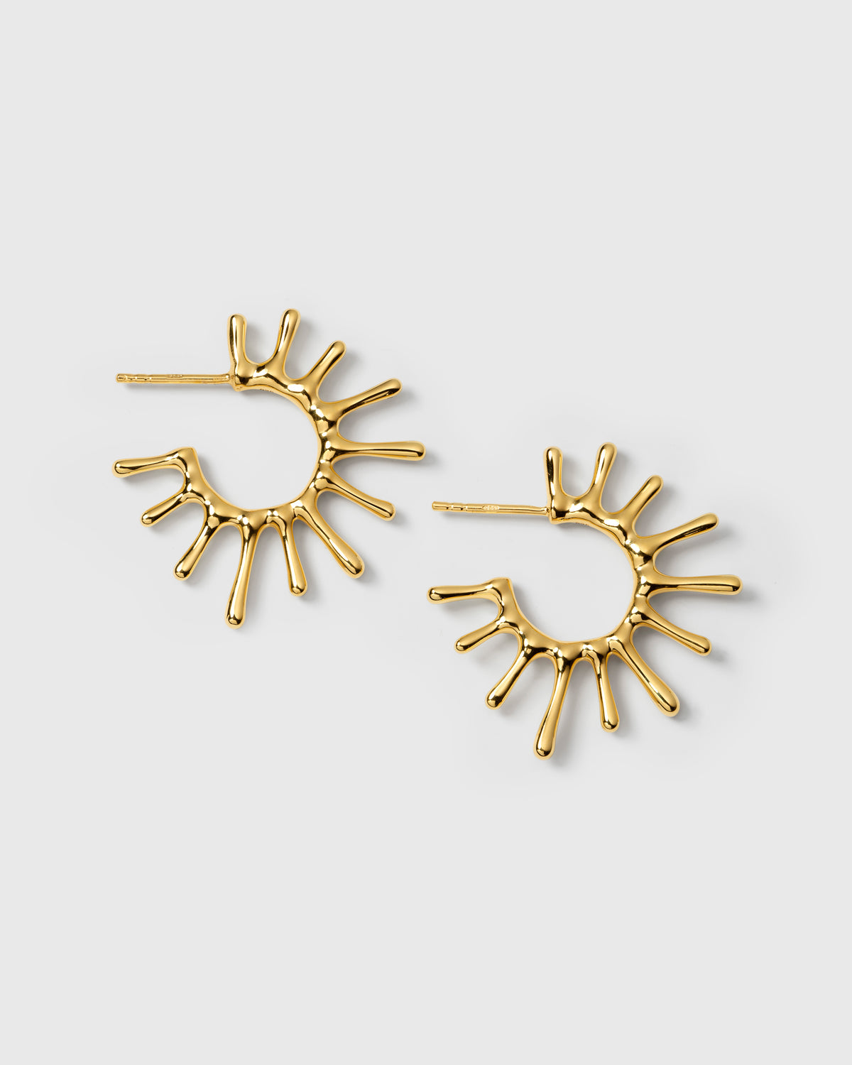 A product shot of the Florentina Big Earrings in gold, showcasing their unique sun-inspired hoop design.
