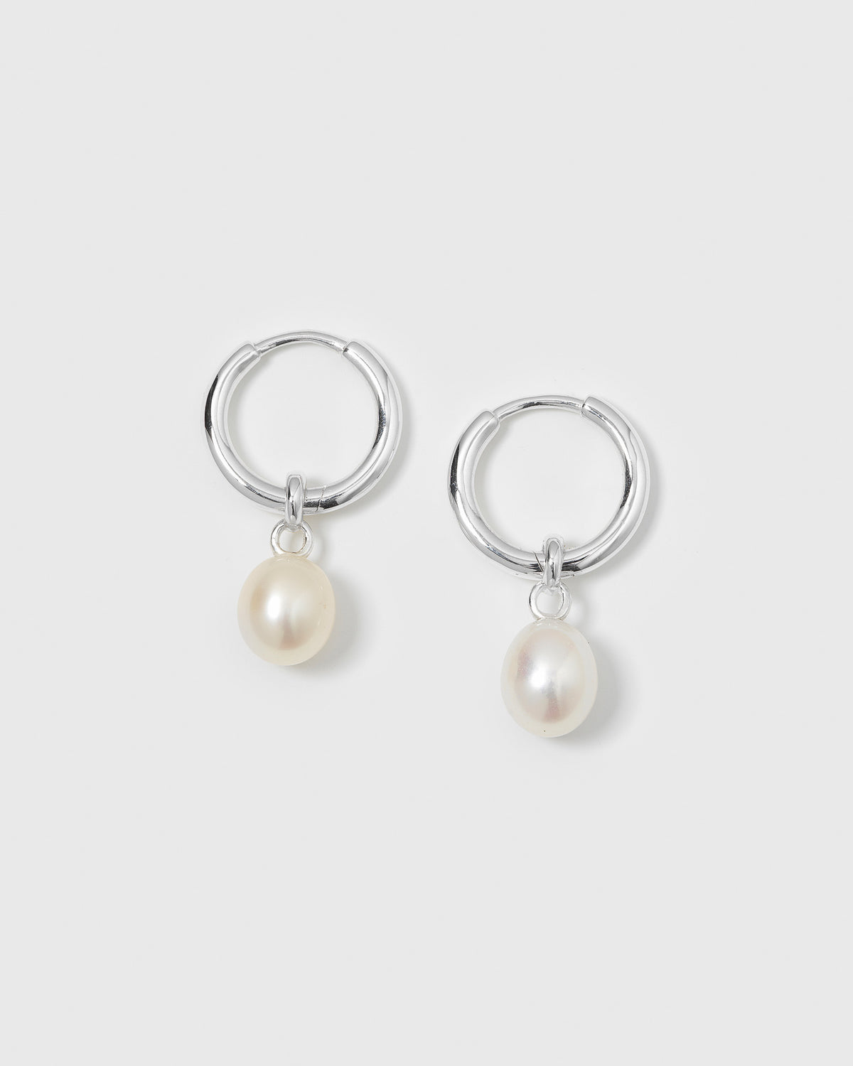 A product shot of the Treasure Pearl Hoops Silver, showing the pair of sterling silver hoops, each with a dangling freshwater pearl.
