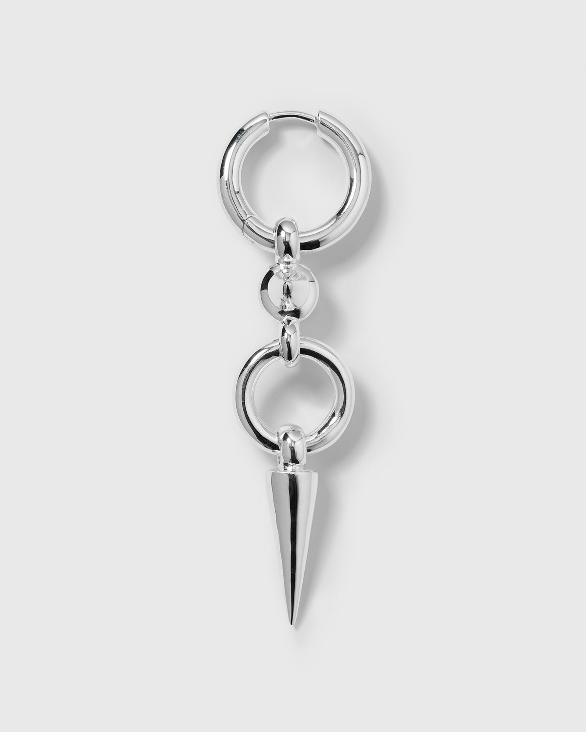 A product shot of the Juno Long Single Earring in silver, featuring a chunky hoop with a long dangle composed of interlocking rings and a pointed spike.