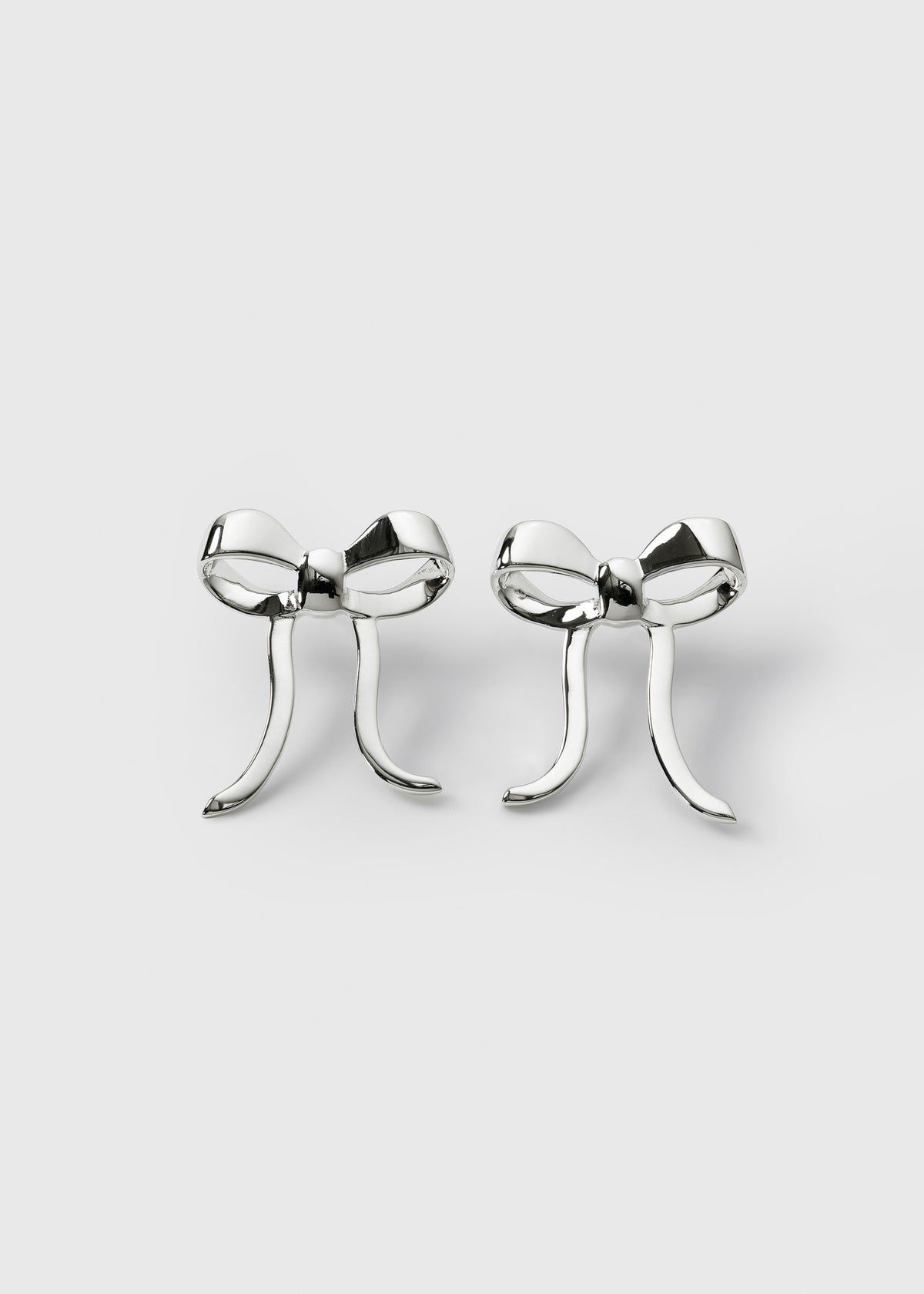 A product shot of the Rosie Earrings in silver, a pair of studs designed as large, elegant bows.