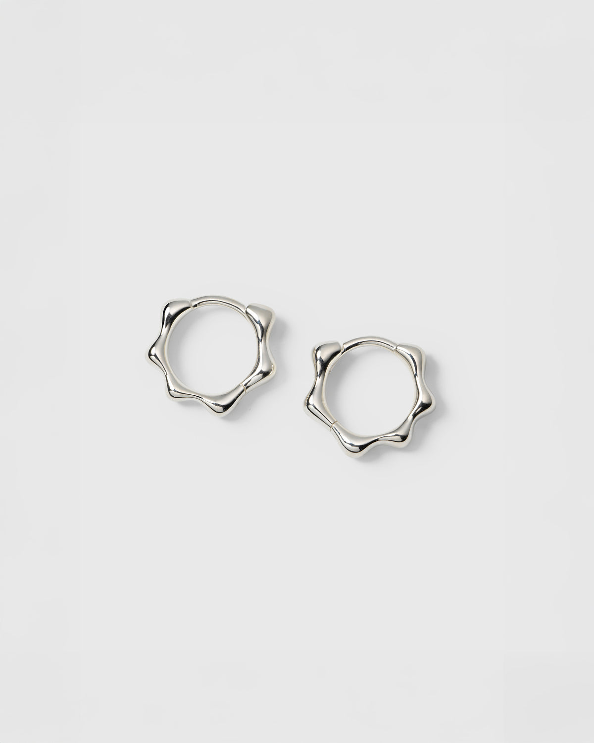 A product shot of the Florentina Small Hoops in silver, showcasing their beautiful and unique wavy pattern.