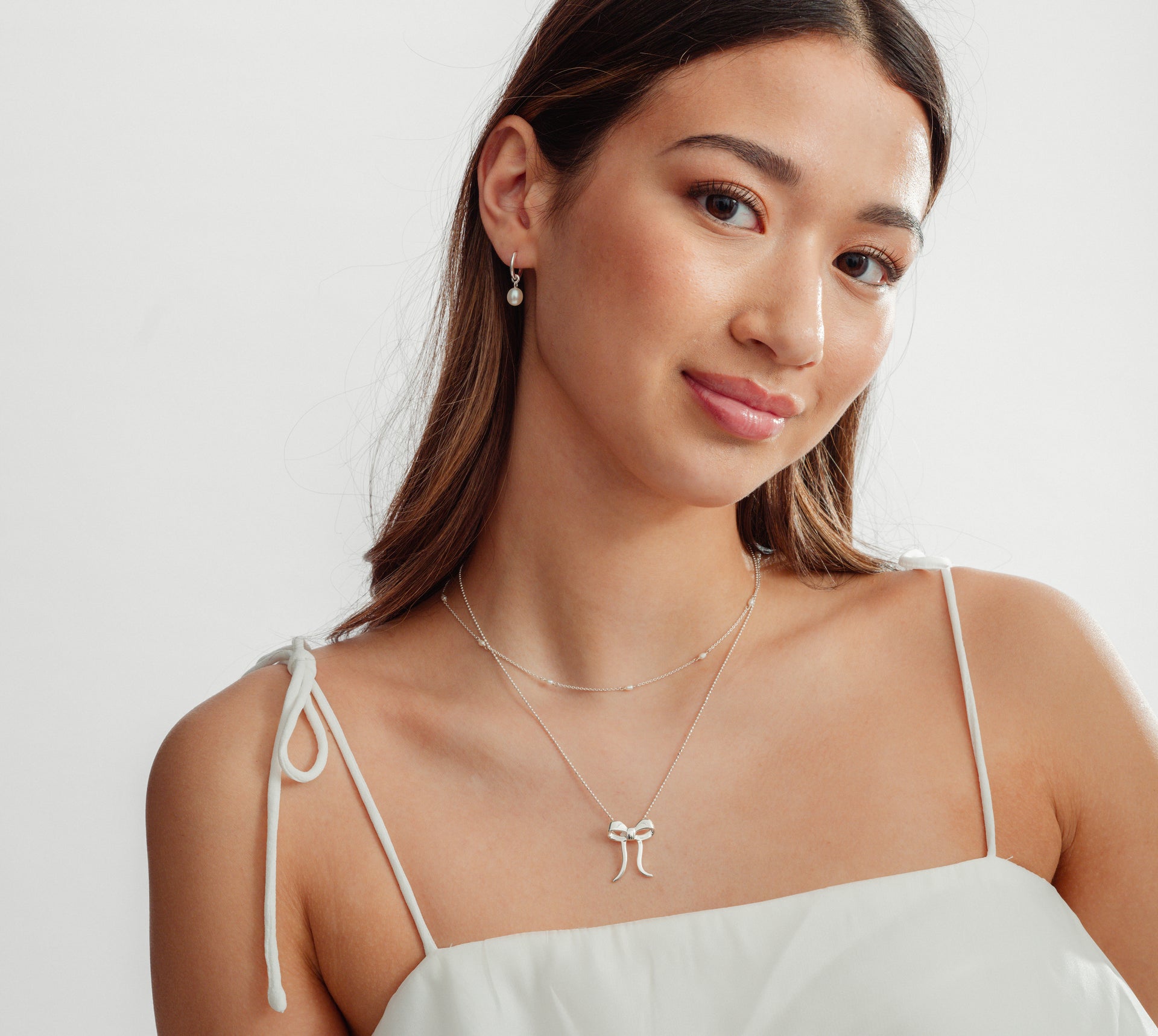 Girl with silver necklaces with pearls and bows and pearl earrings