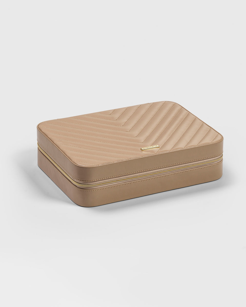 A product shot of the Syster P large jewelry case in beige, featuring a stitched chevron pattern on the lid and a gold-colored zipper.