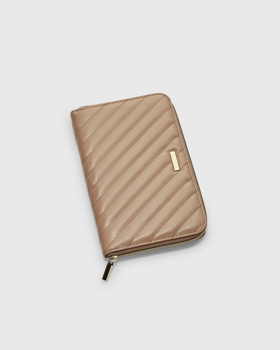 A product shot of the Jewelry Travel Case in beige, showcasing its quilted vegan leather exterior, gold zipper, and Syster P logo tag.