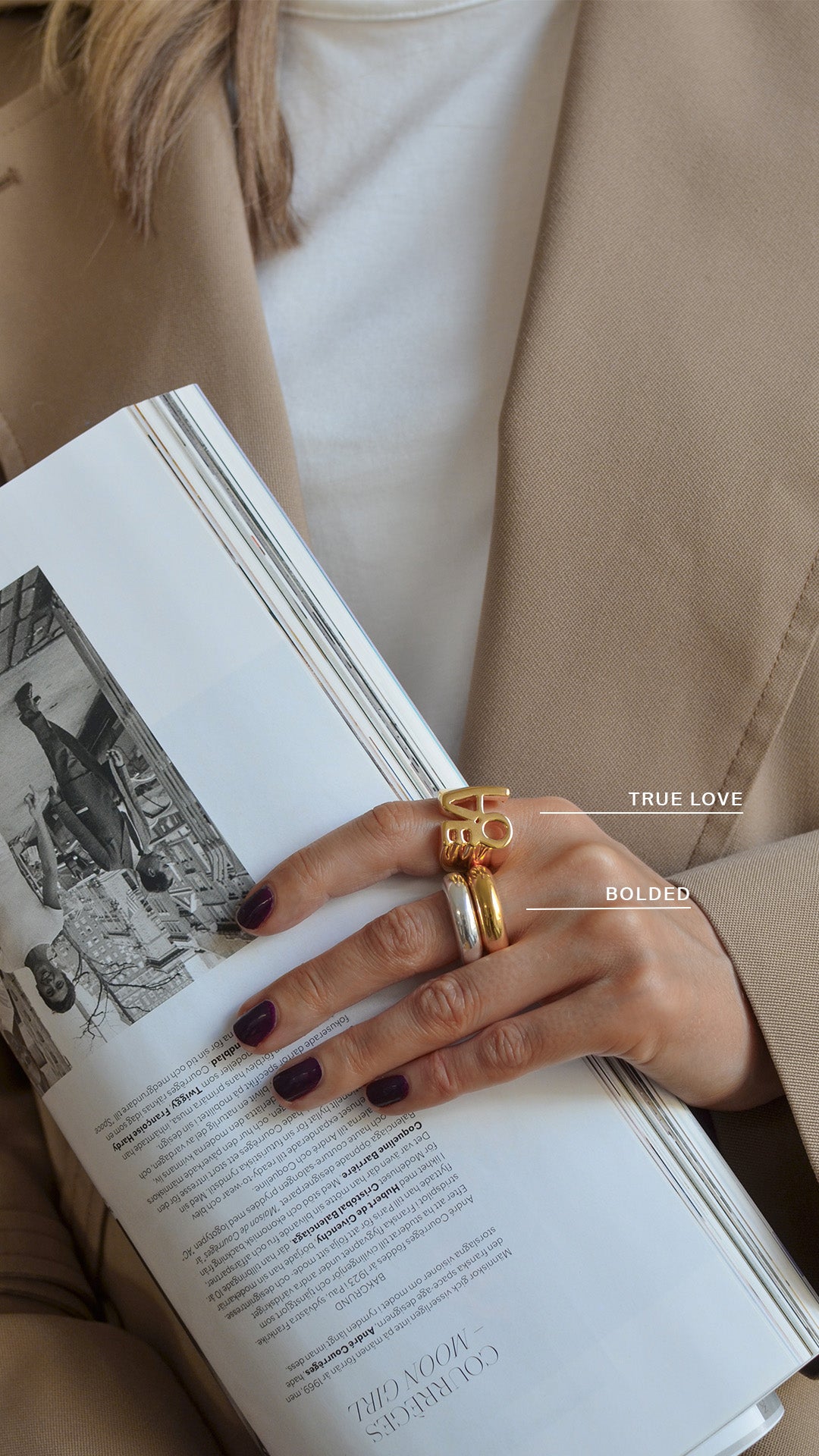 A hand with three rings on it: one bolded silver ring, one gold ring, and one big gold ring with the word "love"