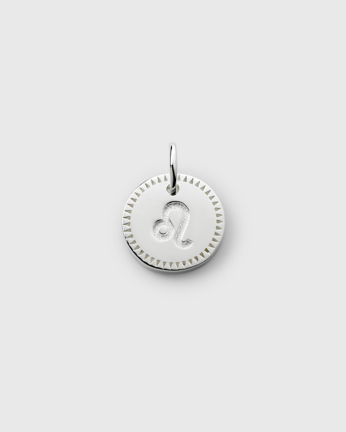 A product shot of the Beloved Zodie Pendant in silver, featuring the circular charm with the engraved Leo zodiac symbol and a decorative triangular border.