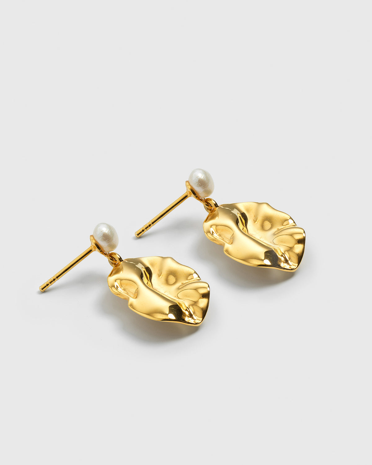 A product shot of the Moulded Short Earrings in gold, showcasing their design of an irregularly shaped, textured pendant dangling from a freshwater pearl stud.