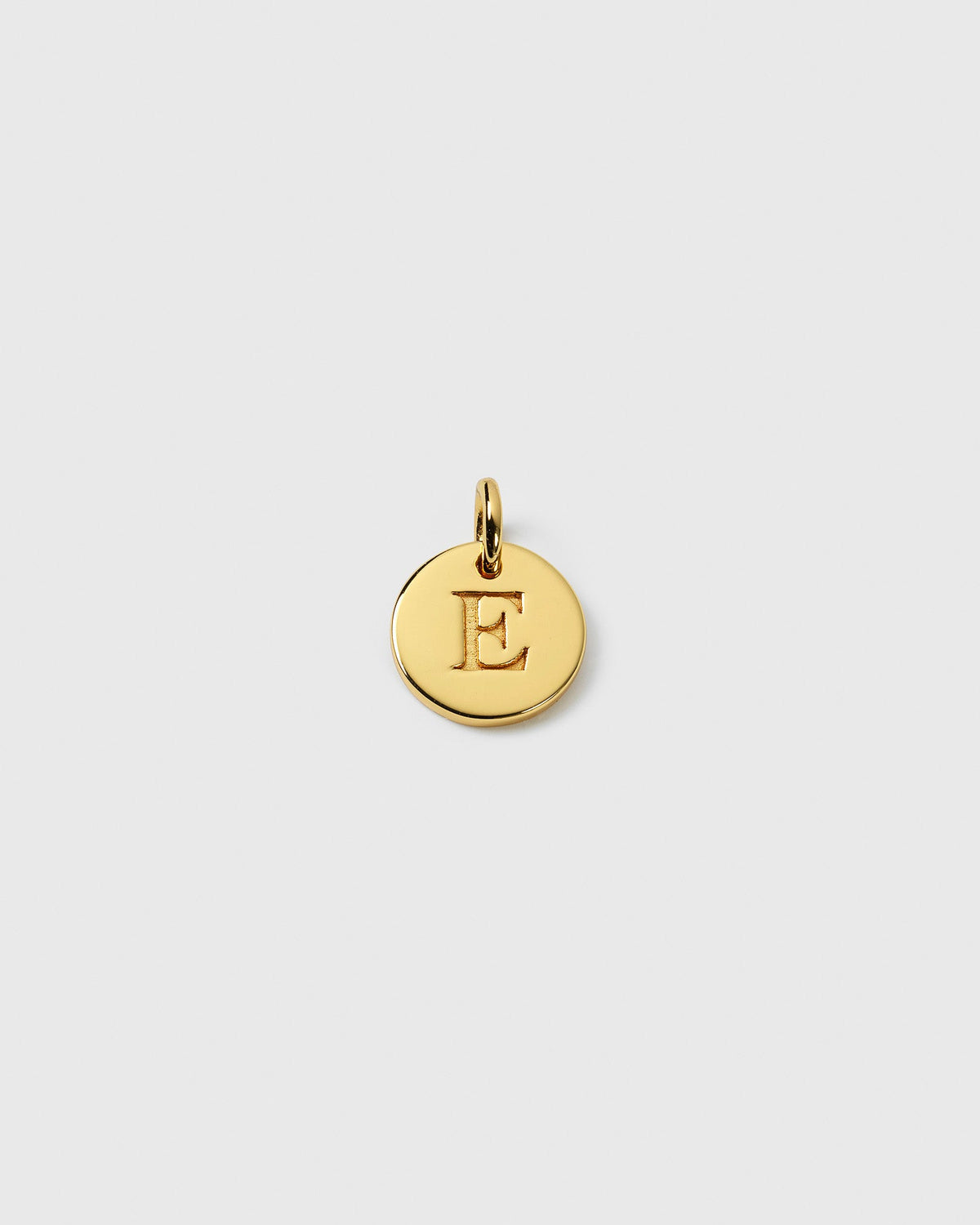 A close-up of the Beloved Mini Letter Gold charm, showing the letter 'E' engraved onto the small, round pendant.