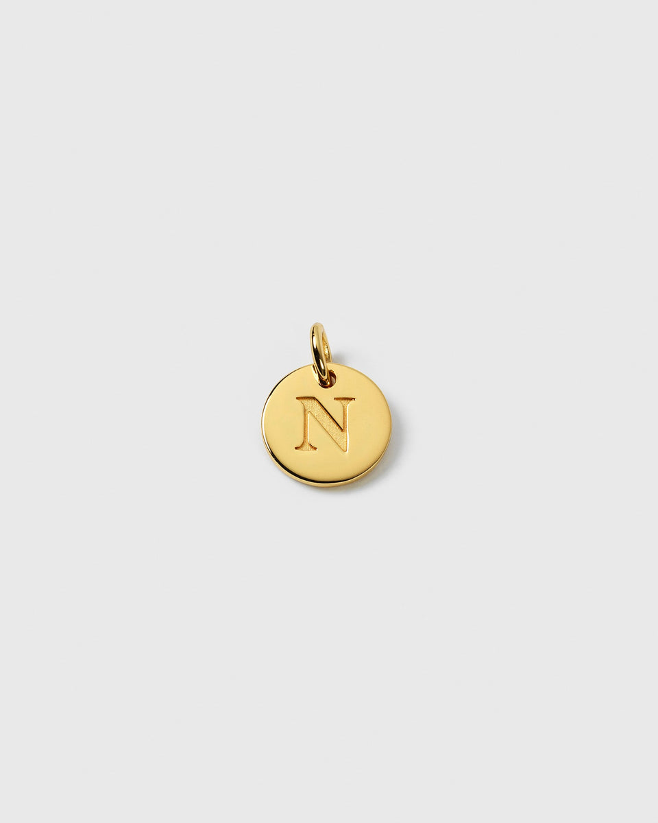 A product shot of the Beloved Mini Letter Gold charm, featuring the letter 'N' engraved on a small, round pendant.