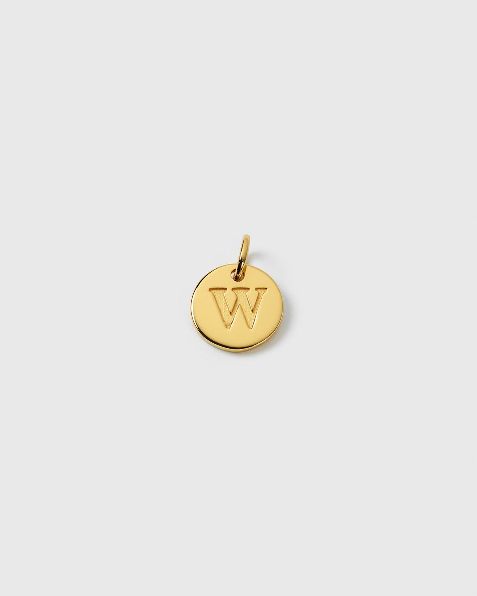 A product shot of the Beloved Mini Letter Gold pendant, a small circular charm with the letter 'W' engraved in the center.