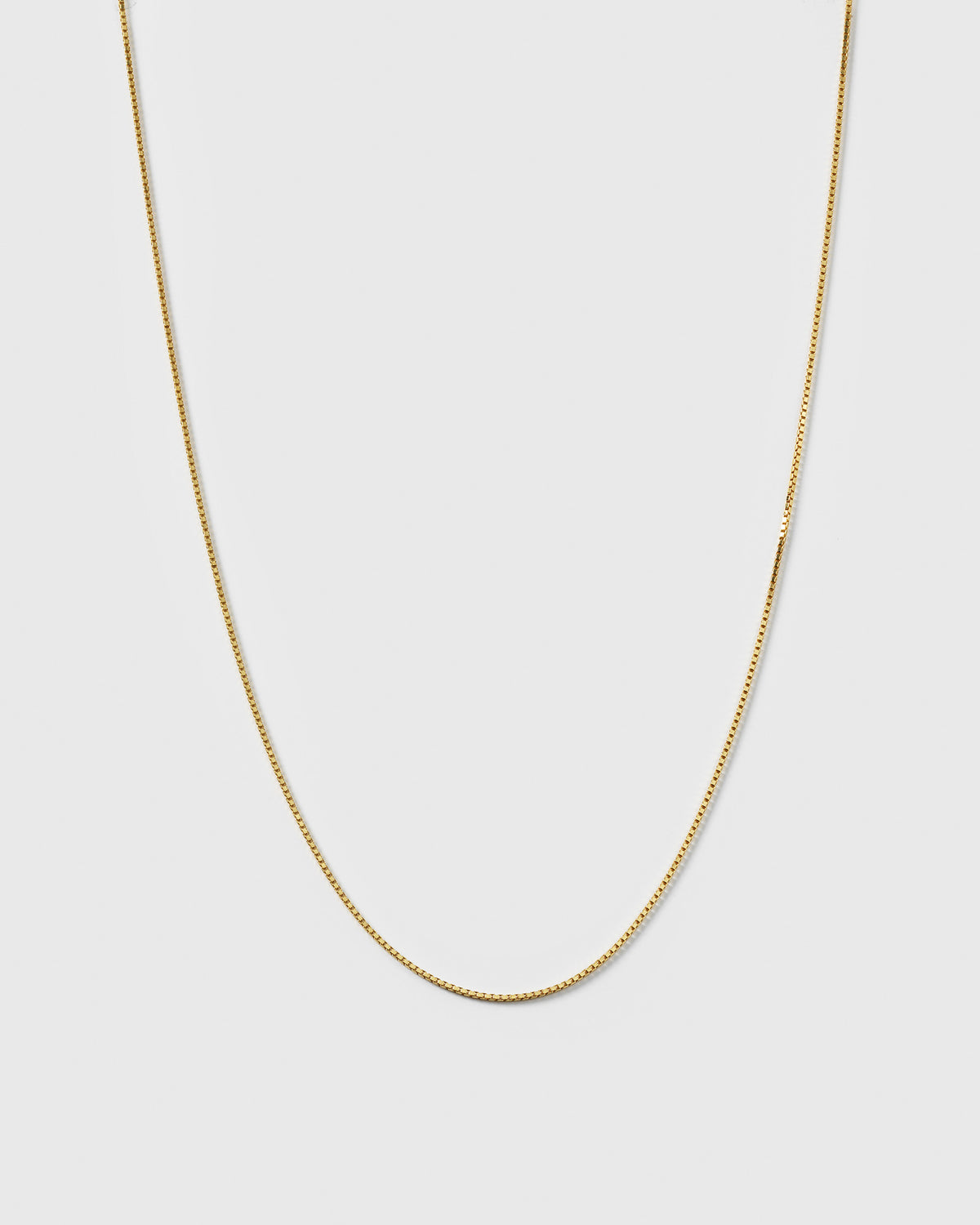 A product shot of the Beloved Long Box Chain in gold, hanging in a U-shape to display its fine box link design.