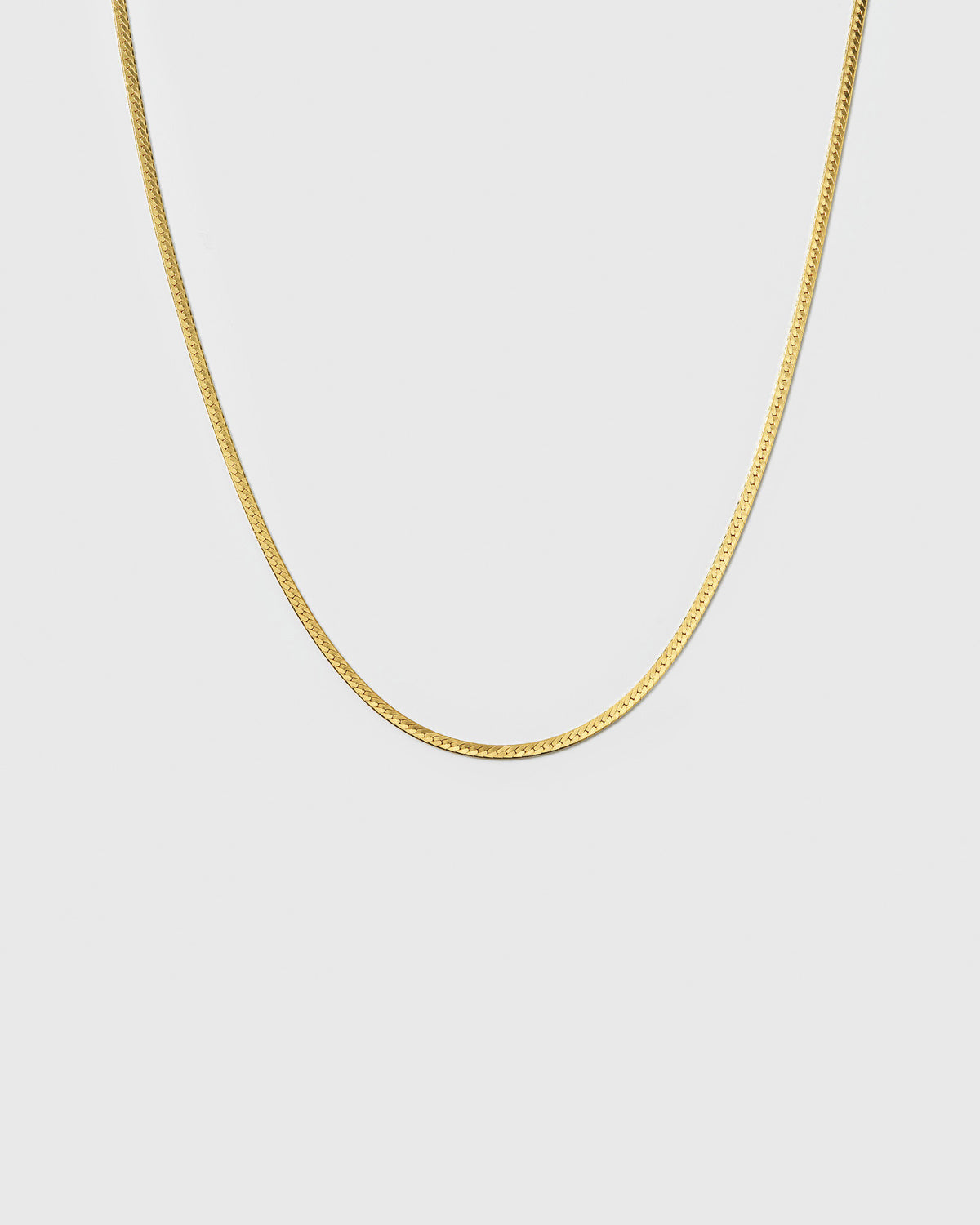 A product shot of the Herringbone Necklace Gold, highlighting its smooth, delicate, and flat chain with a classic herringbone pattern.