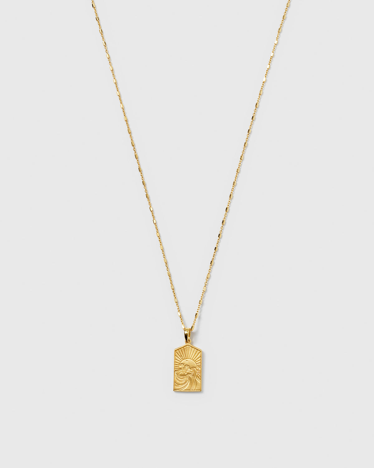 A product shot of the Lucky Coin Keep Dreaming Necklace in gold, featuring a delicate chain and a rectangular pendant with an engraved paradise scene.