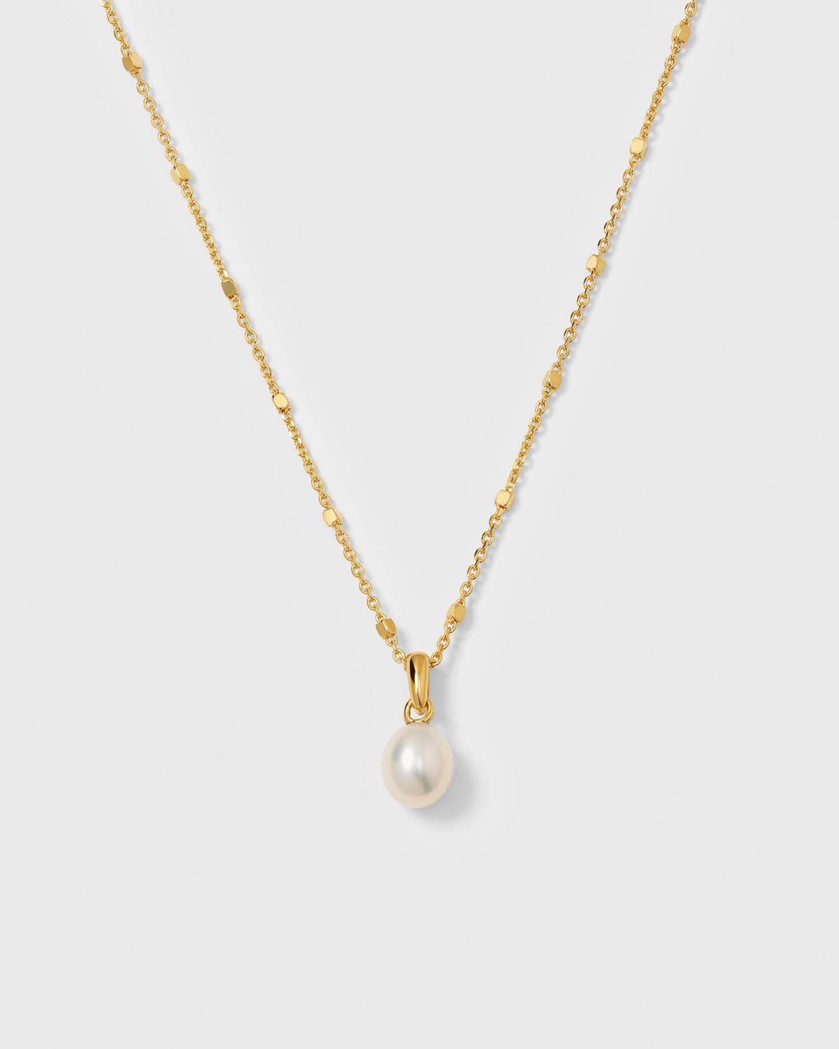 A product shot of the Treasure Single Pearl Necklace in gold, highlighting its unique chain and its single teardrop-shaped freshwater pearl pendant.