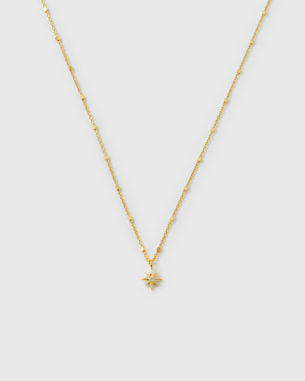A product shot of the North Star Necklace in gold, featuring a unique, delicate chain and a star-shaped pendant set with a clear crystal.
