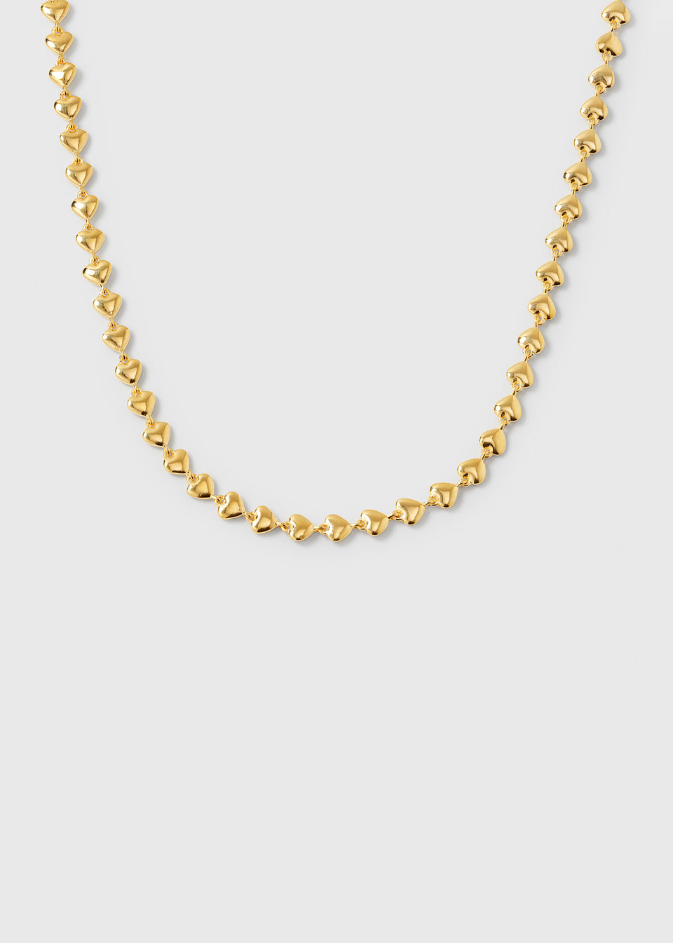 A product shot of the Darling Necklace in gold, showing its design of a chain made up of small, interconnected hearts.