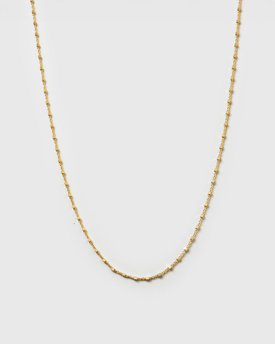 A product shot of the Sheer Station Necklace in gold, featuring a delicate station chain with tiny, shining dots.