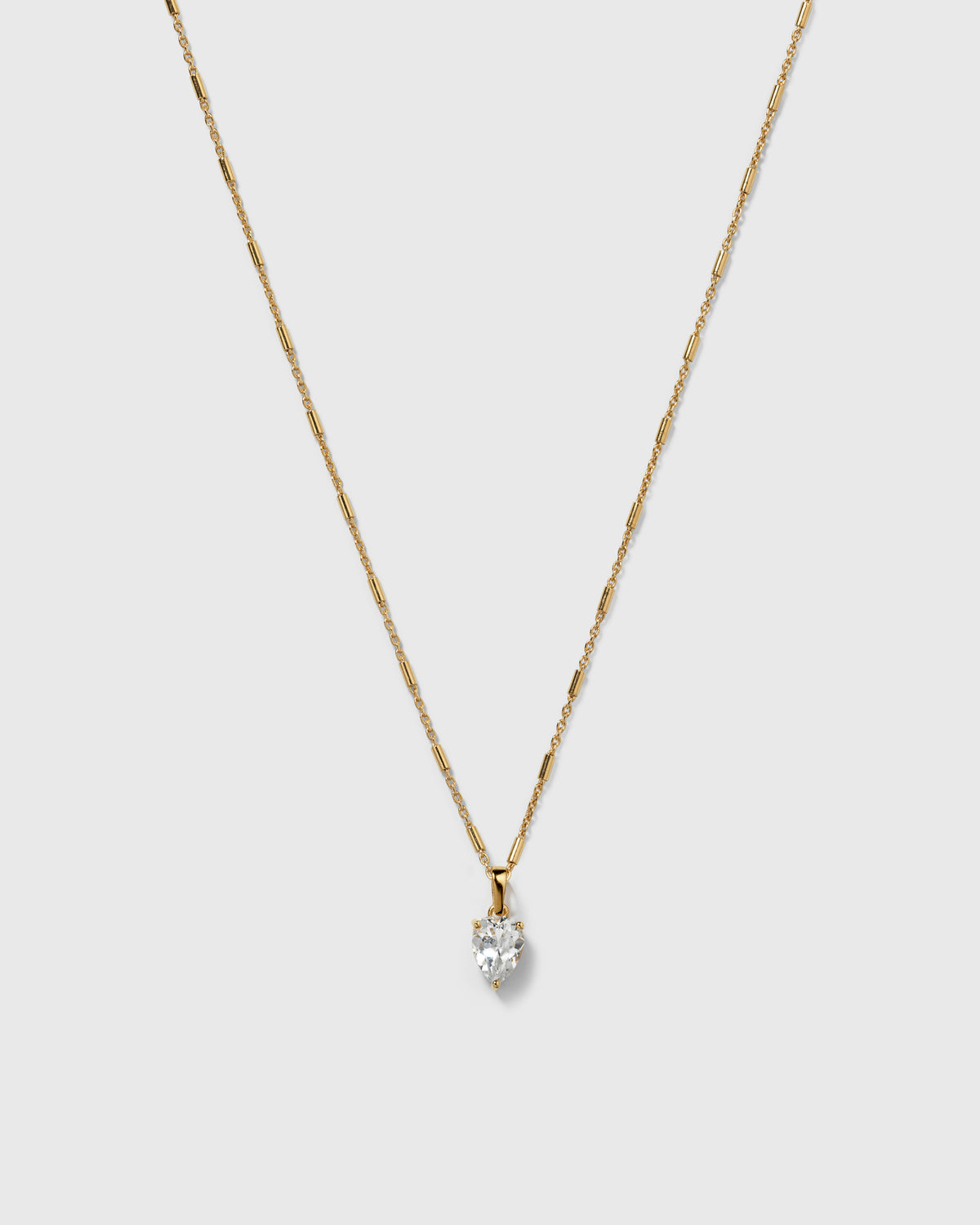 A product shot of the Katie Necklace in gold, featuring its unique chain with bar-like links and a drop-shaped pendant with a set cubic zirconia stone.