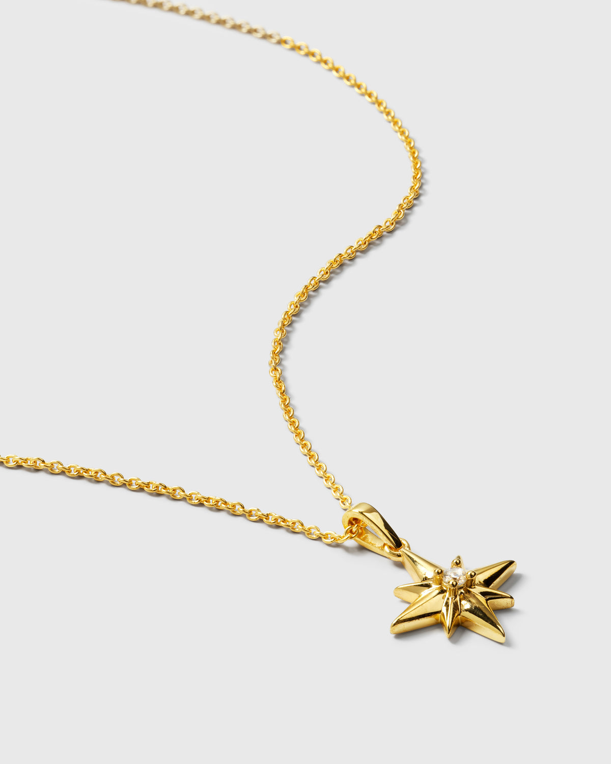 A product shot of the North Star Big Necklace in gold, featuring its delicate chain and a star-shaped pendant with a clear crystal at the center.