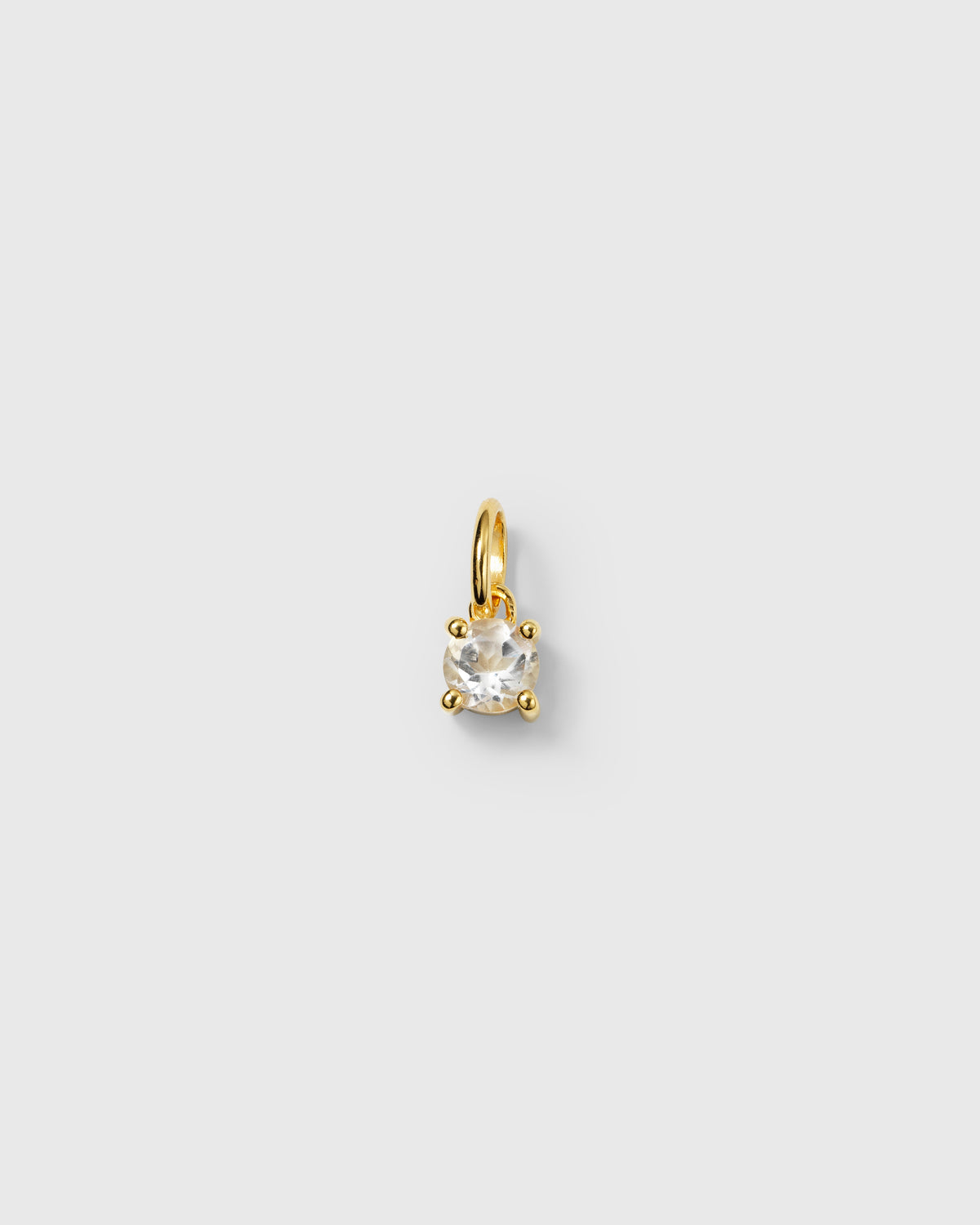 A product shot of the Beloved Solo Nova Pendant in gold, showcasing its round white topaz stone held in a four-prong setting.
