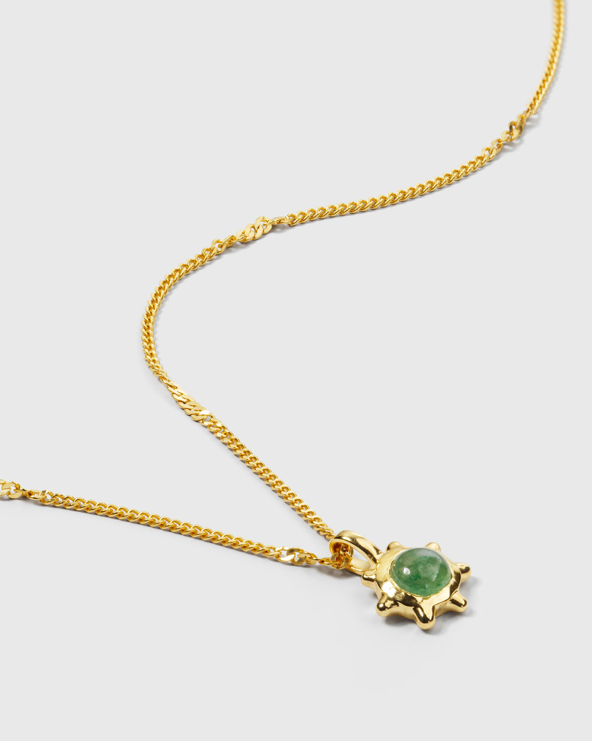 A product shot of the Florentina Necklace Gold, featuring a twisted link chain and a flower-shaped pendant with a central green jade stone.